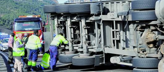 ACCIDENTE. Los operarios trabajan para retirar el camión y la carga de veinticinco toneladas de cebada que transportaba cuando volcó en Despeñaperros. 